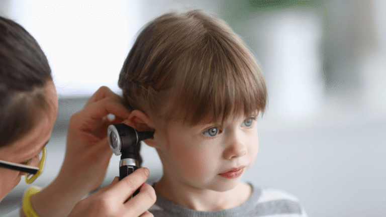 Pediatrician exploring a child's ear in consultation for possible otitis