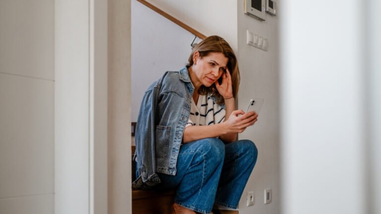 Eine besorgte Frau mittleren Alters, die auf ihrem Handy ihre Symptome der Perimenopause nachschlägt